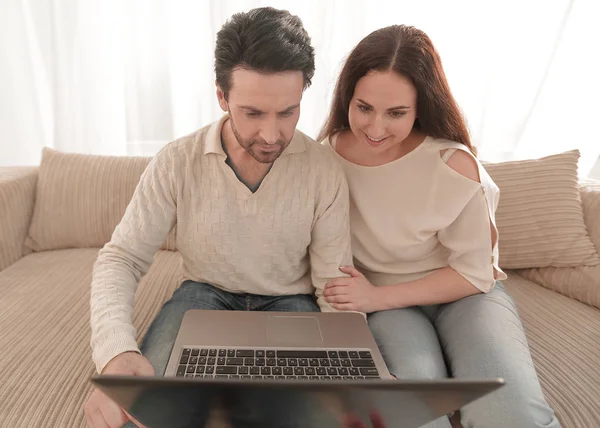 Couple with laptop sitting in the living room on the sofa — Stock Photo, Image