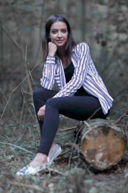 Ormanın içinde bir günlük üzerinde oturan genç kadın.