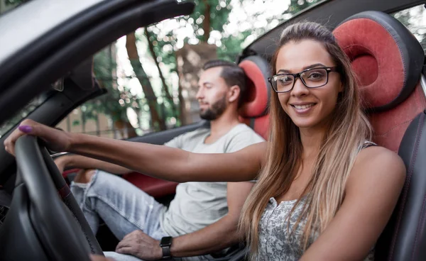 Jovem mulher moderna sentada ao volante de um carro conversível — Fotografia de Stock