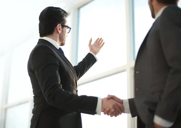 Close up. businessmen shaking hands during a conversation in the office — Stock Photo, Image