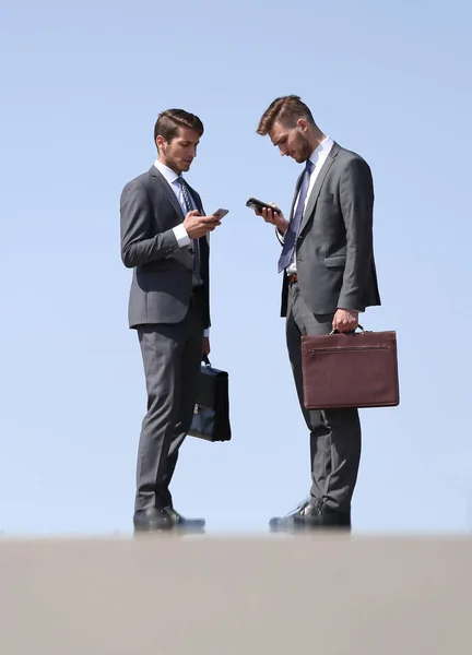 Affärskollegor med mobiltelefoner som stående på gatan — Stockfoto