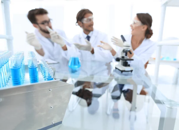 Фоновое изображение ученых, изучающих голубую жидкость во фляжке — стоковое фото