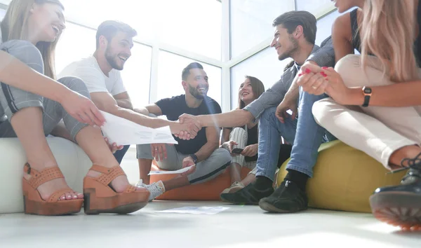 Vänner som skakar hand, sitter på golvet i det nya kontoret — Stockfoto