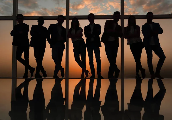 Silhouette di un team di lavoro in piedi accanto alla finestra dell'ufficio — Foto Stock