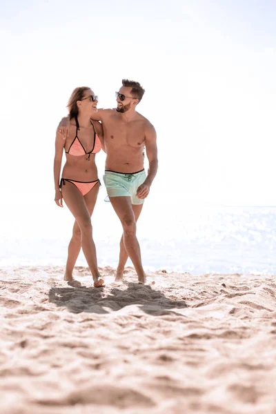 Young couple holding hands and walking on beach. — Stock Photo, Image