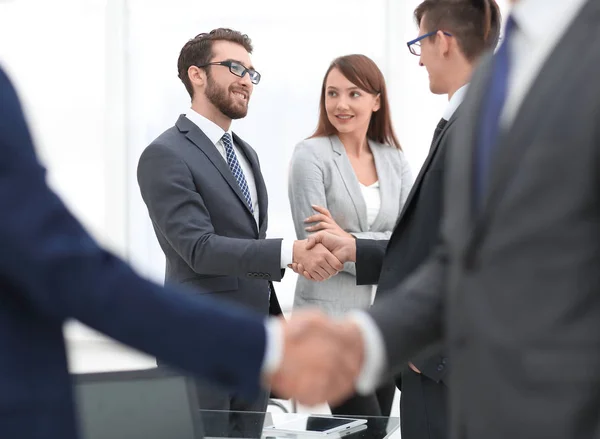 Twee zakenmannen schudden handen met collega 's op de achtergrond. — Stockfoto