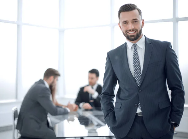 Young businessman standing in a bright office — Stock Photo, Image