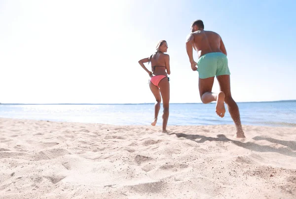 Lyckliga par körs på tropisk strand vid solnedgången, semester — Stockfoto