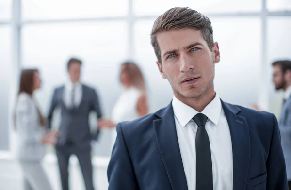 Уверенный молодой бизнесмен на размытом офисном фоне — стоковое фото