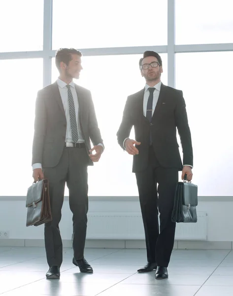 Muito longe. dois homens de negócios estão andando no lobby do escritório — Fotografia de Stock