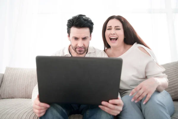 Casal feliz sentado no sofá e usando laptop em casa — Fotografia de Stock