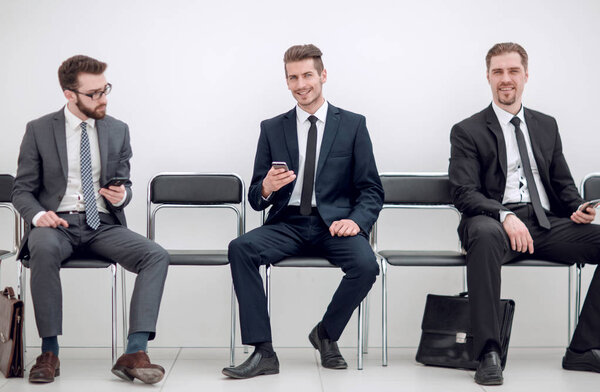 группа деловых людей, сидящих в офисном коридоре
