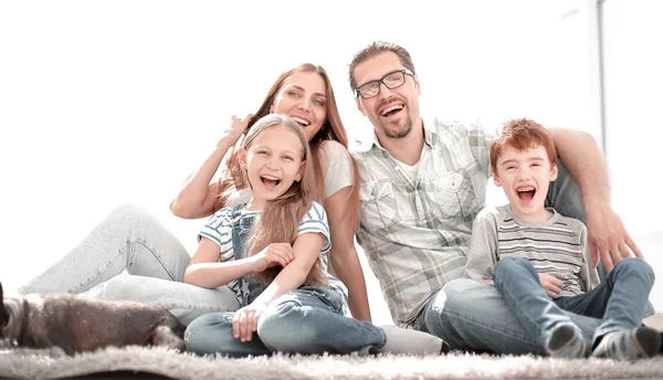 Familia alegre sentado en la alfombra en la nueva sala de estar —  Fotos de Stock