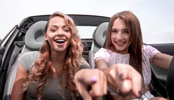 Dos chicas felices sentadas en el coche y apuntándote —  Fotos de Stock