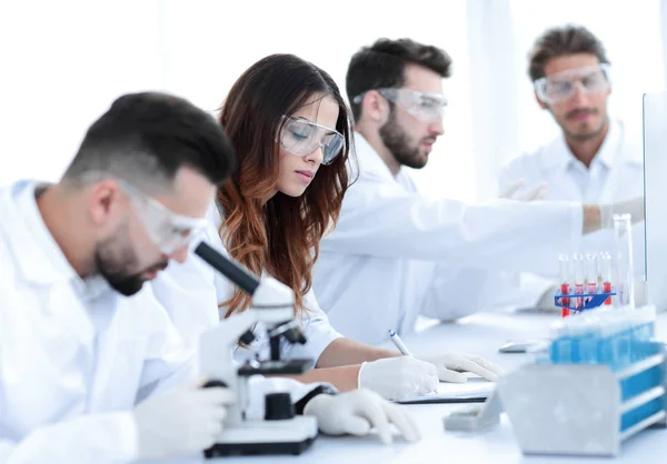 Científico mirando en un microscopio sentado en el laboratorio . — Foto de Stock