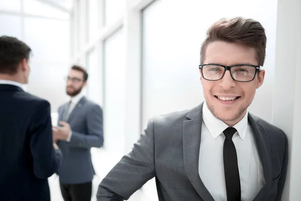 Joven hombre de negocios con gafas de pie en la oficina del pasillo — Foto de Stock