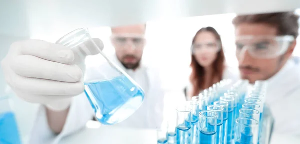 Closeup.a grupo de cientistas estudando o líquido no tubo de vidro — Fotografia de Stock