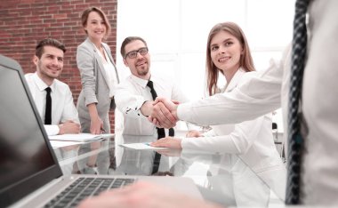 Ofis masaları el sıkışan iş adamları.