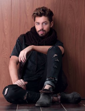 Tuğla duvarın yanında oturan yakışıklı olgun adam. Erkek modası.