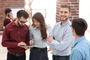 Bir grup insan iş planlarını tabletle tartışıyor..