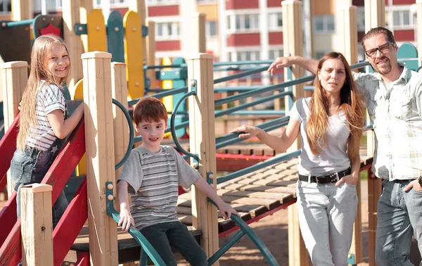 Ung familj med barn som har roligt på lekplatsen — Stockfoto