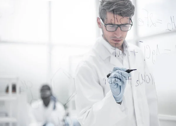 Científico haciendo notas en el tablero de cristal en el momento del experimento — Foto de Stock