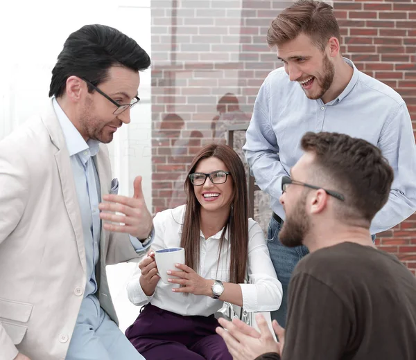 Jovens empresários estão conversando e sorrindo durante a pausa para o café no escritório — Fotografia de Stock