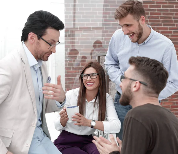 Jóvenes empresarios están hablando y sonriendo durante la pausa para el café en la oficina — Foto de Stock