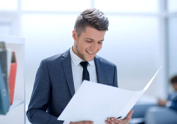 Lächelnder Geschäftsmann beim Lesen einiger Dokumente am Arbeitsplatz — Stockfoto