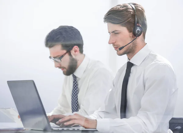 Manager with the headset uses a laptop to work with the client — Stock Photo, Image