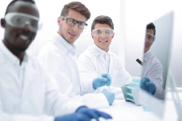 Groupe réussi de scientifiques assis à leur bureau — Photo