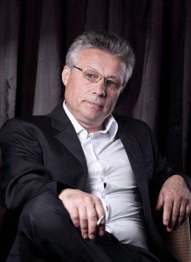 bir sandalyede oturan bir sigara ile üst düzey iş adamı