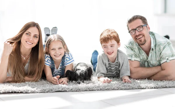 Föräldrar med barn som ljuger i vardagsrummet på mattan. — Stockfoto