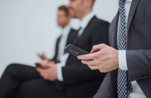 Affärsman med en smartphone som sitter i office receptionen — Stockfoto