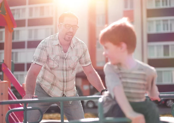 Feliz padre jugando con el niño en el patio de recreo —  Fotos de Stock