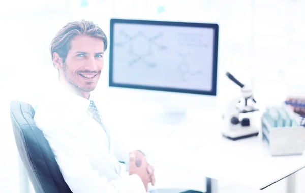 Male scientist sitting at table in laboratory