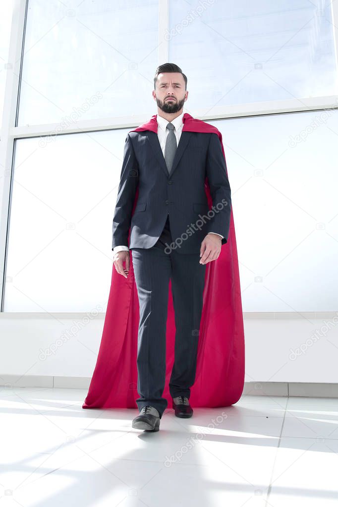 businessman in a Superman cloak standing in a bright office
