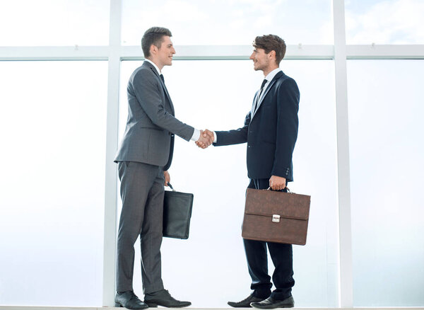 handshake of business partners standing near a large office wind