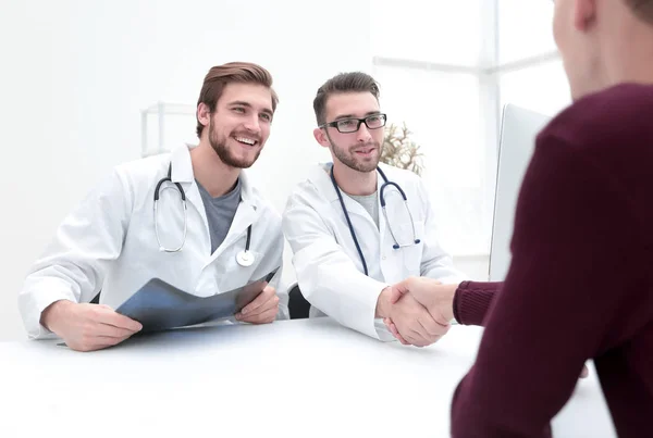 Mosolygó orvos a klinikán, amely egy kézfogás, hogy a beteg — Stock Fotó