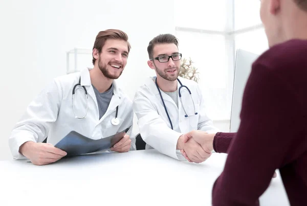 Leende läkare på kliniken ger en handskakning till sin patient — Stockfoto