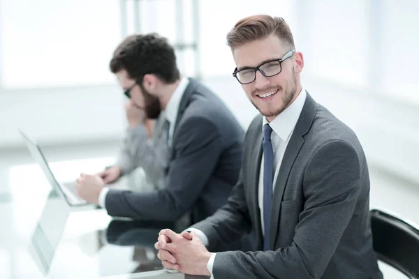 Vista laterale. uomo d'affari sorridente sullo sfondo del posto di lavoro — Foto Stock