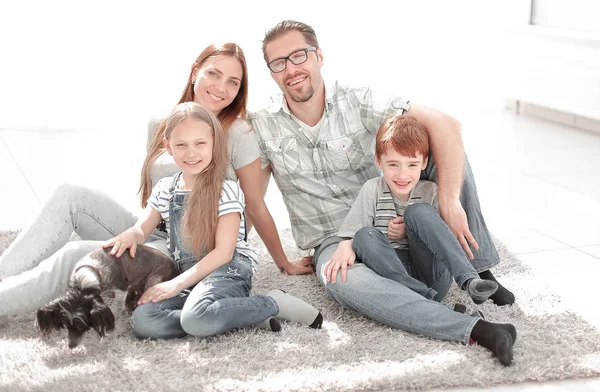 Família feliz sentado no tapete em um novo apartamento — Fotografia de Stock