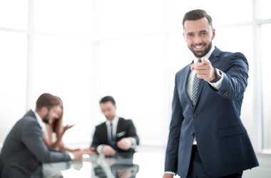 ofiste ayakta ve sana işaret gülümseyen iş adamı