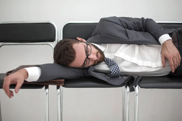 Homem de negócios cansado dormindo em cadeiras no corredor do escritório — Fotografia de Stock
