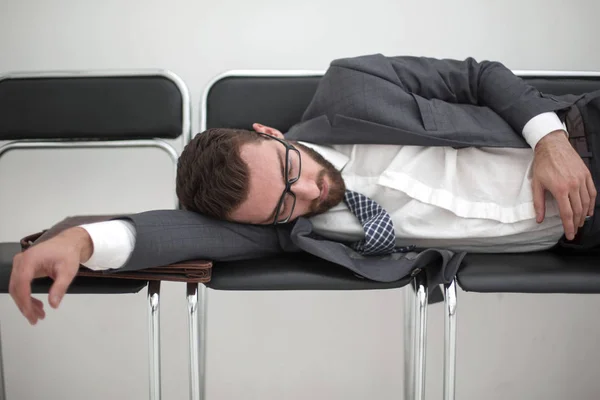 tired businessman sleeping on chairs in the office hallway