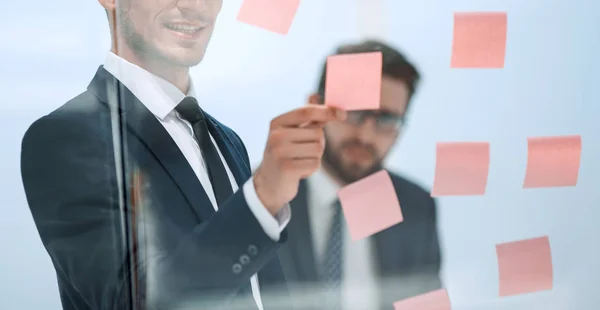 Seriöser Mitarbeiter liest Aufkleber-Zettel auf der Bürotafel. — Stockfoto