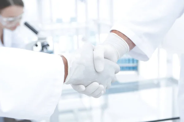 Doctors in lab coats greeting each other with handshake — Stock Photo, Image