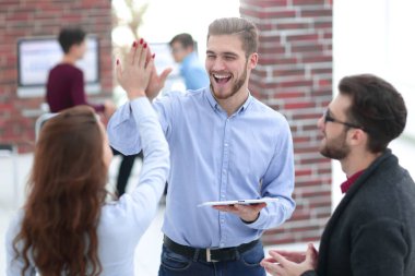 Fotoğraf bir tablet basılı tutup vererek mutlu genç iş adamları