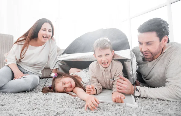 Happy parents play with children in a tent in the living room — Stock Photo, Image