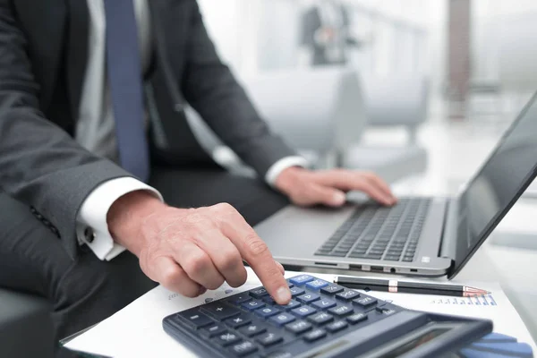 Close up.a homem de negócios usa uma calculadora e um laptop . — Fotografia de Stock